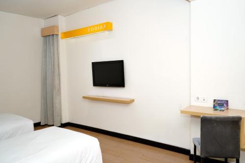 a hotel room with a bed and a tv on the wall at Zodiak Paskal by KAGUM Hotels in Bandung