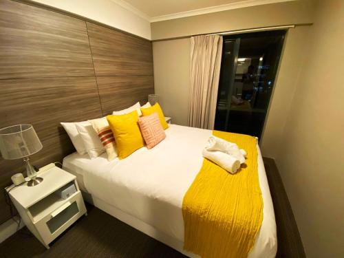 1 dormitorio con 1 cama grande con almohadas amarillas en 2 Beds 2 Baths Apt In Braddon CBD - Pool, 1 Free Parking, Gym, en Canberra