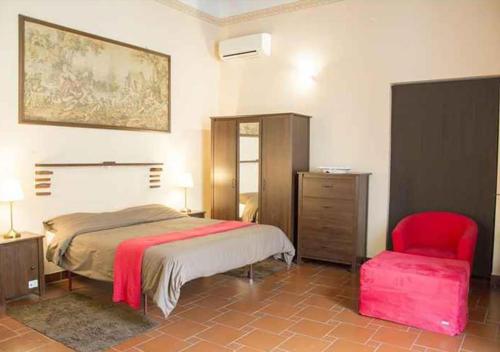 - une chambre avec un lit et une chaise rouge dans l'établissement B&B Peruzzi Rooms, à Civitavecchia