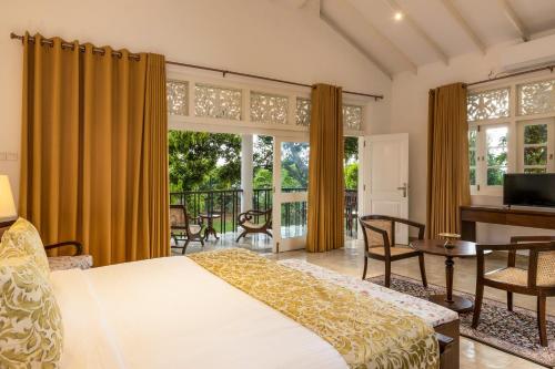 a bedroom with a bed and a desk and windows at Villa Labugolla in Kandy