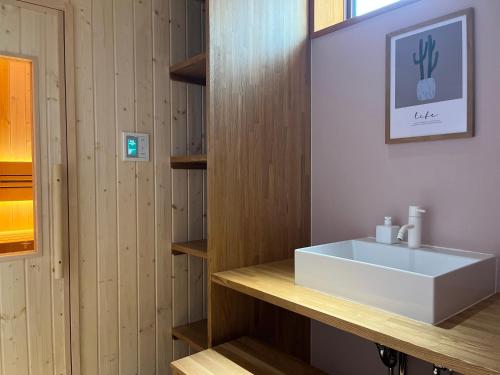 a bathroom with a white sink and wooden walls at MY LODGE Naoshima in Naoshima