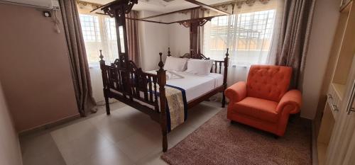 ein Schlafzimmer mit einem Bett und einem orangenen Stuhl in der Unterkunft The Festival Fully Furnished Apartments in Mombasa