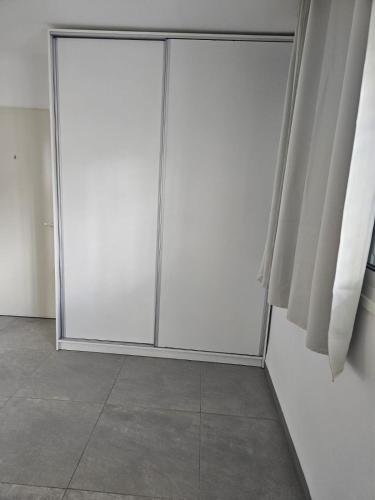 biała szafa z dwoma przesuwnymi drzwiami w pokoju w obiekcie Rina House w mieście Karmiel
