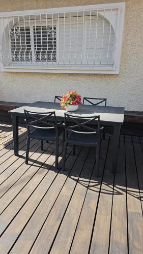 uma mesa com duas cadeiras e um vaso de flores num deque em Rina House em Karmiel