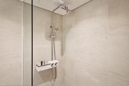 a shower with a shower head in a bathroom at Ramada Encore by Wyndham Gimpo Han River Hotel in Gimpo