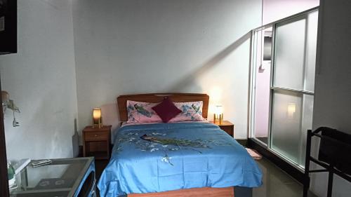 a bedroom with a bed with blue sheets and a window at Palms Villa in Negombo