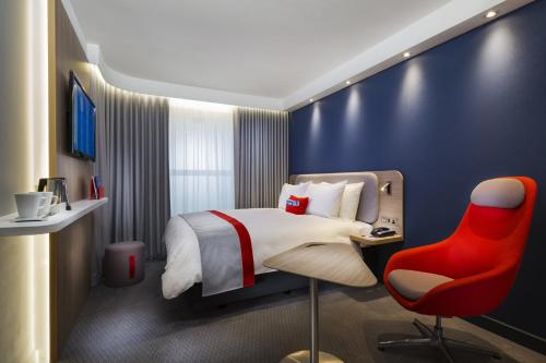 a hotel room with a bed and a red chair at Holiday Inn Express - Krefeld - Dusseldorf by IHG in Krefeld