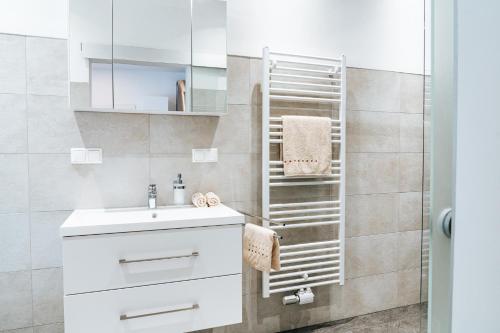 La salle de bains est pourvue d'un lavabo blanc et d'une douche. dans l'établissement Gemütliche Wohnung im Zentrum, à Zeltweg