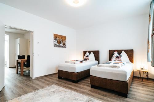 two beds in a room with white walls and wooden floors at Gemütliche Wohnung im Zentrum in Zeltweg