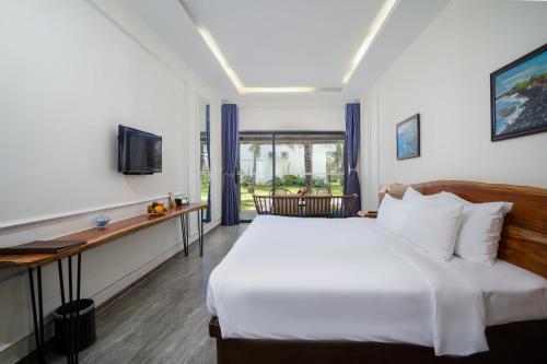 a bedroom with a bed and a desk and a television at Sala Tuy Hoa Beach Hotel in Tuy Hoa