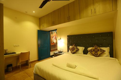 a bedroom with a large white bed and a desk at Zingle Stay Airport Hotel in Chennai