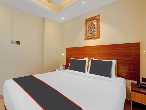 a bedroom with a large white bed with a wooden headboard at Pallava Rajadhani in Trivandrum