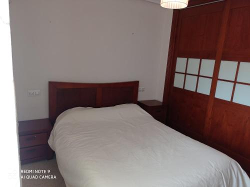 アンドゥハルにあるPiso taxi estación de autobusesの白いベッド1台(木製ヘッドボード付)が備わるベッドルーム1室が備わります。