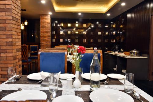 a table with white plates and a vase of flowers at Rufina Pinasa Residency in Gangtok