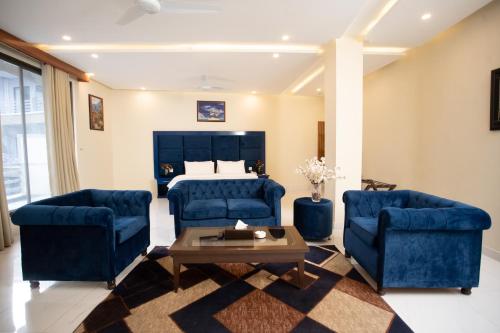 a living room with two blue chairs and a bed at Hotel One Swat in Swat