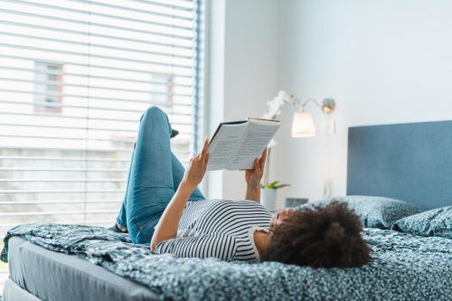 Eine Frau, die auf einem Bett liegt und ein Buch liest. in der Unterkunft Apartments Villa Popp in Ljubljana