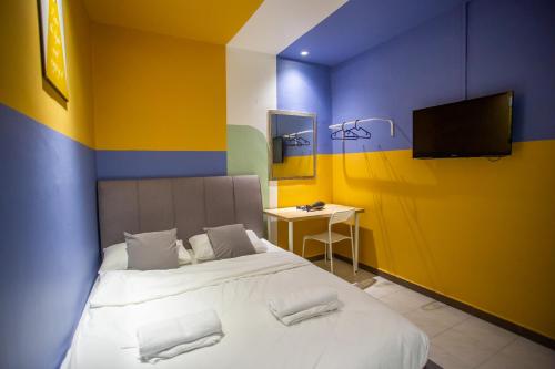 a bedroom with a bed and a tv on the wall at The Cave By Cactus Hotel Skudai in Skudai