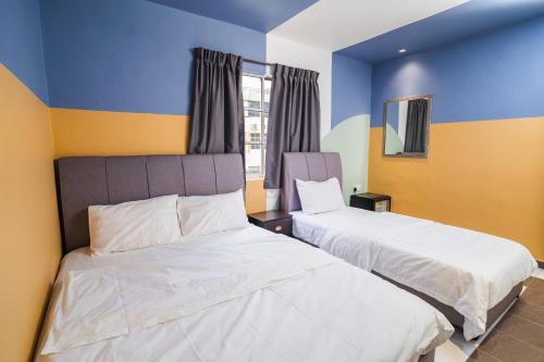 two beds in a room with blue and yellow walls at The Cave By Cactus Hotel Skudai in Skudai