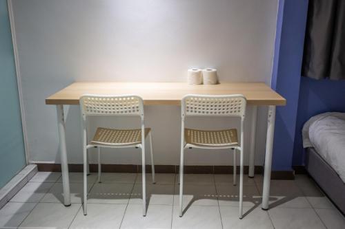 a small table with two chairs next to a bed at The Cave By Cactus Hotel Skudai in Skudai