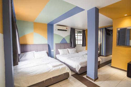 two beds in a room with a colorful wall at The Cave By Cactus Hotel Skudai in Skudai