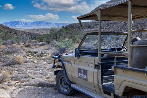 a jeep parked in the desert with mountains in the background at Rooiberg Lodge in Van Wyksdorp