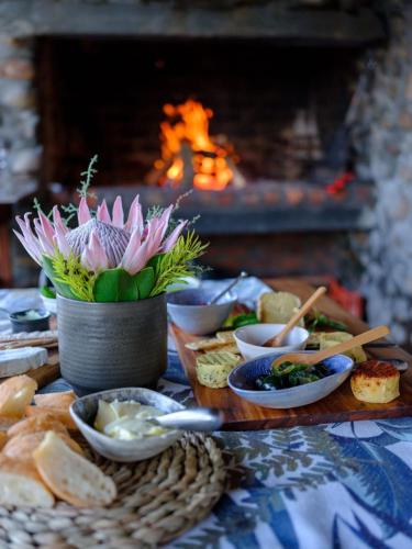 a table with plates of food and a flower in a vase at River Edge in Romansrivier