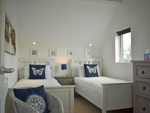 2 letti in una camera da letto con cuscini bianchi e blu di Swallows Cottage a Churston Ferrers