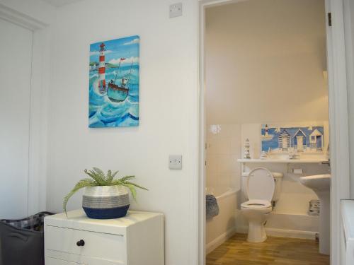La salle de bains est pourvue de toilettes et d'une peinture murale. dans l'établissement Swallows Cottage, à Churston Ferrers
