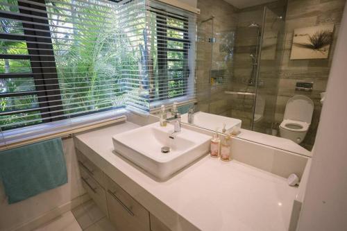 een badkamer met een wastafel, een douche en een spiegel bij Bayview Apartment Grand Bay in Grand Baie