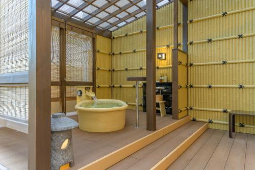 a bathroom with a tub in a room with yellow walls at ホテル京都エミナースManyonoyuHotelKyotoEminence in Kyoto