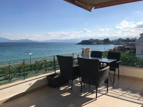 balcón con mesa y sillas y vistas al océano en Golden Coast Panagias Apartment en Volos
