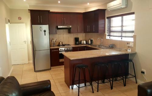 a kitchen with a refrigerator and a counter with bar stools at Beach Apartment Melkbosstrand in Melkbosstrand