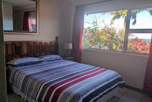a bedroom with a bed and a large window at Indigo Chalets in Port Edward