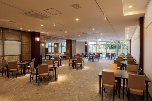 a restaurant with tables and chairs in a room at ホテル京都エミナースManyonoyuHotelKyotoEminence in Kyoto