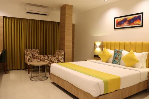 a hotel room with a bed and a table and chairs at Hotel Park Residency Thrissur in Trichūr