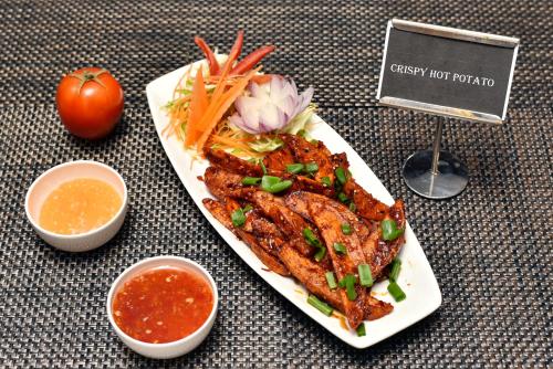 a plate of food with meat and vegetables on a table at Rufina Pinasa Residency in Gangtok