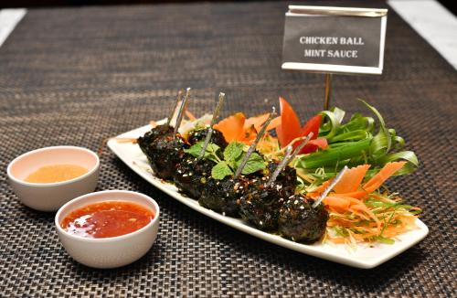 two plates of food on a table with dipping sauces at Rufina Pinasa Residency in Gangtok