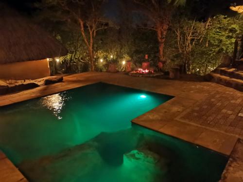 Adorable unique guest house - African bush feel في Kalkheuvel: مسبح في الليل مع موقد نار