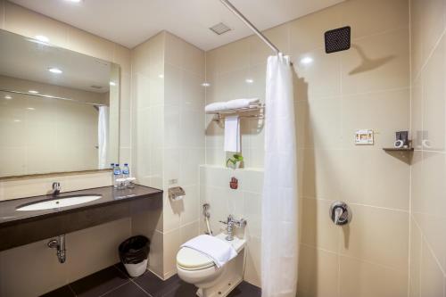 a bathroom with a toilet and a sink and a mirror at Horison Ultima Bandara Balikpapan in Sepinggang-Kecil