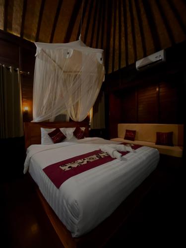 a bedroom with a large bed with a mosquito net at Damara Lembongan in Nusa Lembongan