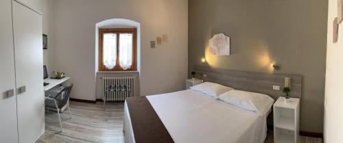 1 dormitorio con 1 cama blanca grande y escritorio en Hotel Mom Assisi, en Asís