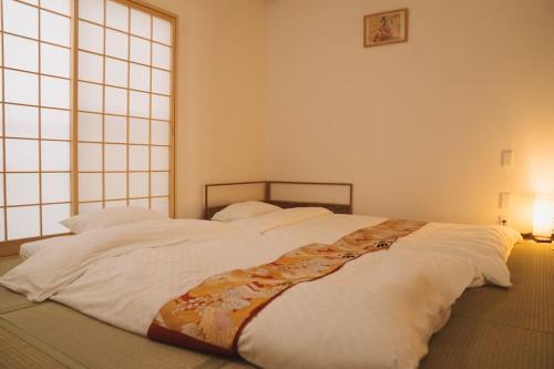 a large white bed in a room with a window at Kokoro no sato・Tsuki in Kyoto