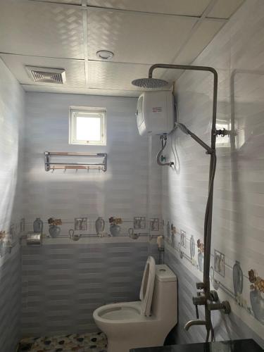 ein weißes Bad mit einem WC und einem Fenster in der Unterkunft Grand Budapest Hotel in Cát Bà