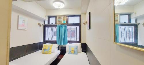 a room with two beds and two windows at Apple Hostel in Hong Kong