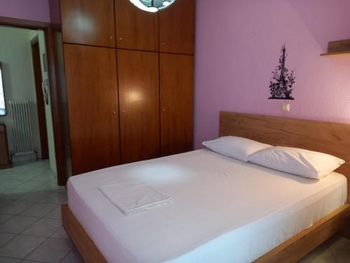 um quarto com uma cama branca e uma parede rosa em Dimos em Tessalónica