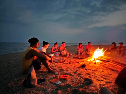 een groep mensen die rond een vuur op het strand zitten bij KRABI BAMBOO KINGDOM at AOLUEK PARADISE in Ao Luk