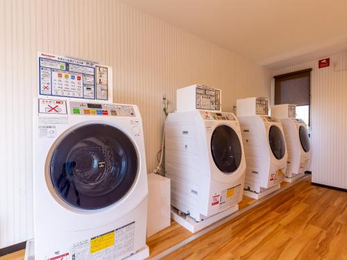 a row of washing machines in a laundry room at HOTEL R9 The Yard Kawaminami in Kawaminami