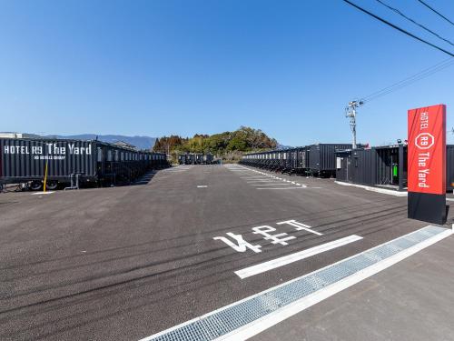 een lege parkeerplaats met veel containers bij HOTEL R9 The Yard Kawaminami in Kawaminami