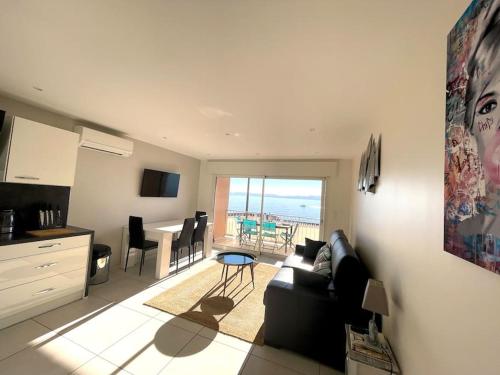 a living room with a couch and a kitchen with a table at Appartement Vue Mer Golfe de Saint-Tropez in Sainte-Maxime