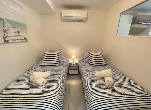 two beds in a room next to each other with pillows at Appartement Vue Mer Golfe de Saint-Tropez in Sainte-Maxime